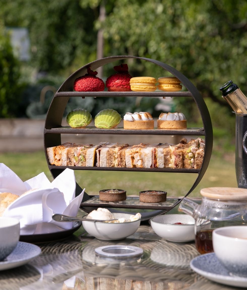 Afternoon tea tier stand with scones, sandwiches, and pastries in The Back Garden