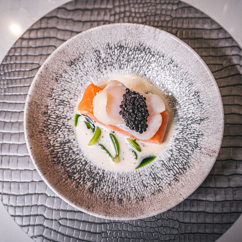 Chef preparing intricate dish course at MO restaurant
